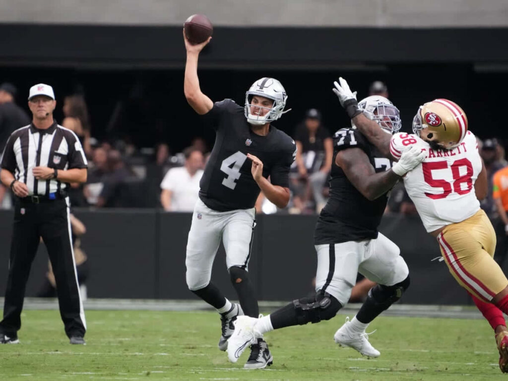 Aidan O'Connell throwing football under pressure in NFL game with defenders closing in and teammates blocking Wallpaper