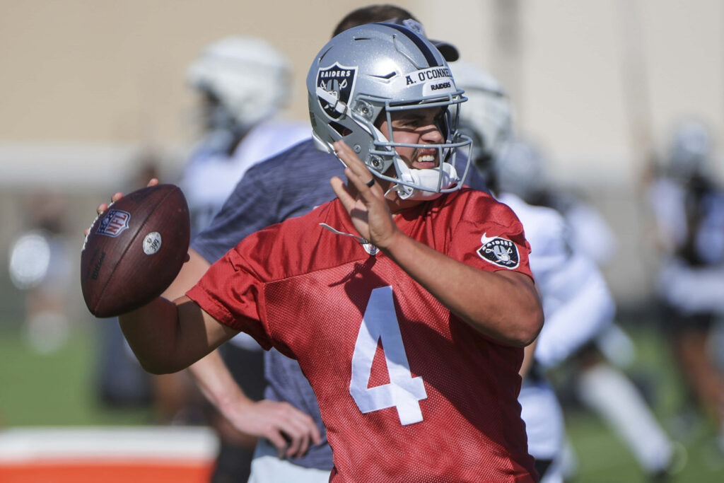 Aidan OConnell focused practicing quarterback throwing technique during intense football training session Wallpaper