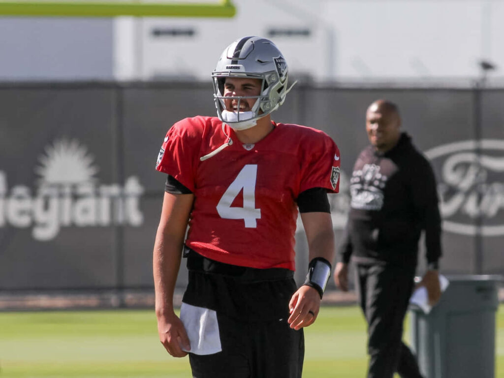 Aidan OConnell in red practice jersey focused during quarterback training session on football field Wallpaper