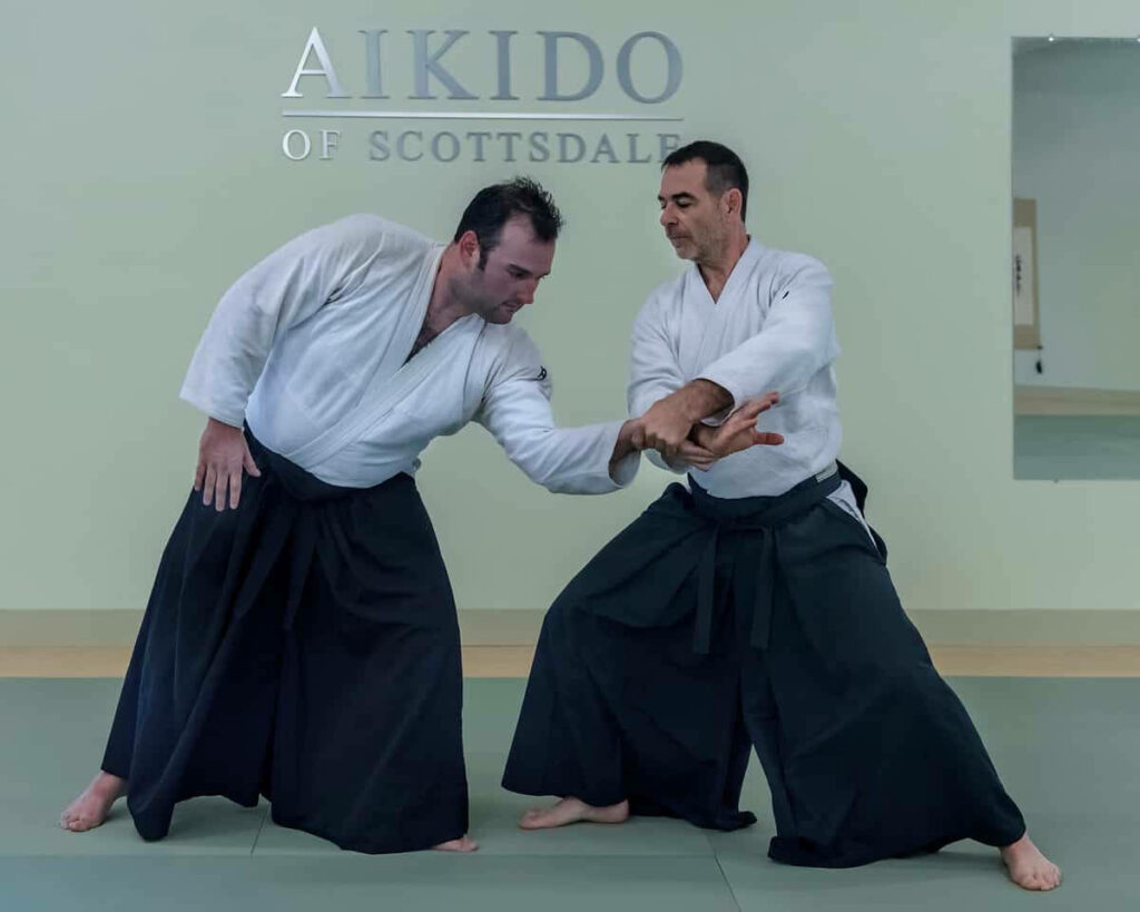 Aikido instructor demonstrating precise Nikyo technique in traditional attire dojo setting wallpaper