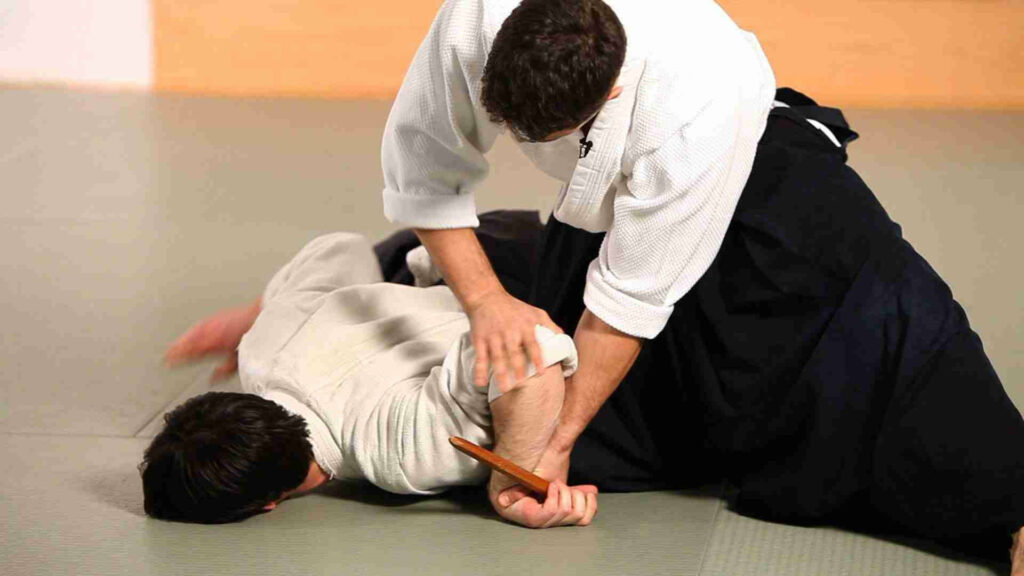 Two Aikido practitioners perform Nikyo technique in traditional dojo showcasing precise movements Wallpaper