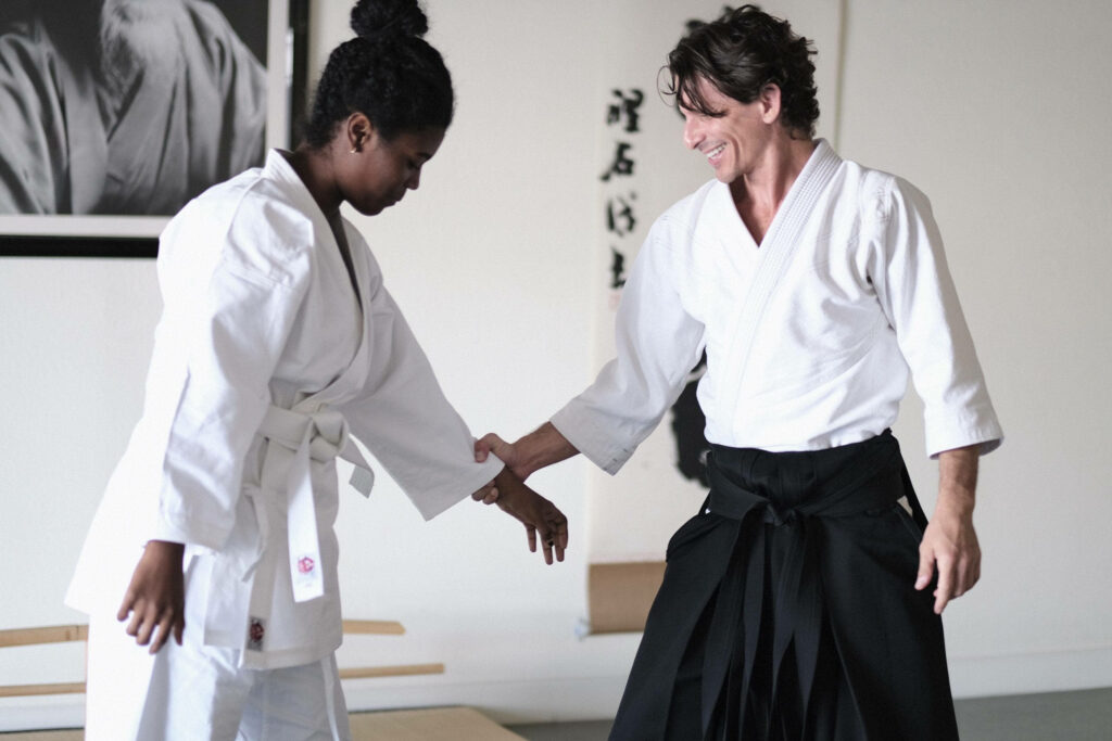 Aikido sensei teaching traditional martial arts techniques to focused student in bright dojo background Wallpaper