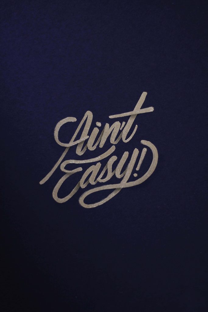 Aesthetic 4K wallpaper with Ain’t Easy gold calligraphy on deep navy blue minimalist background