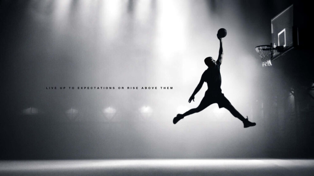 Dusk's Majestic Slam: Michael Jordan Soaring Above the Court with Air Jordan Enigma Wallpaper