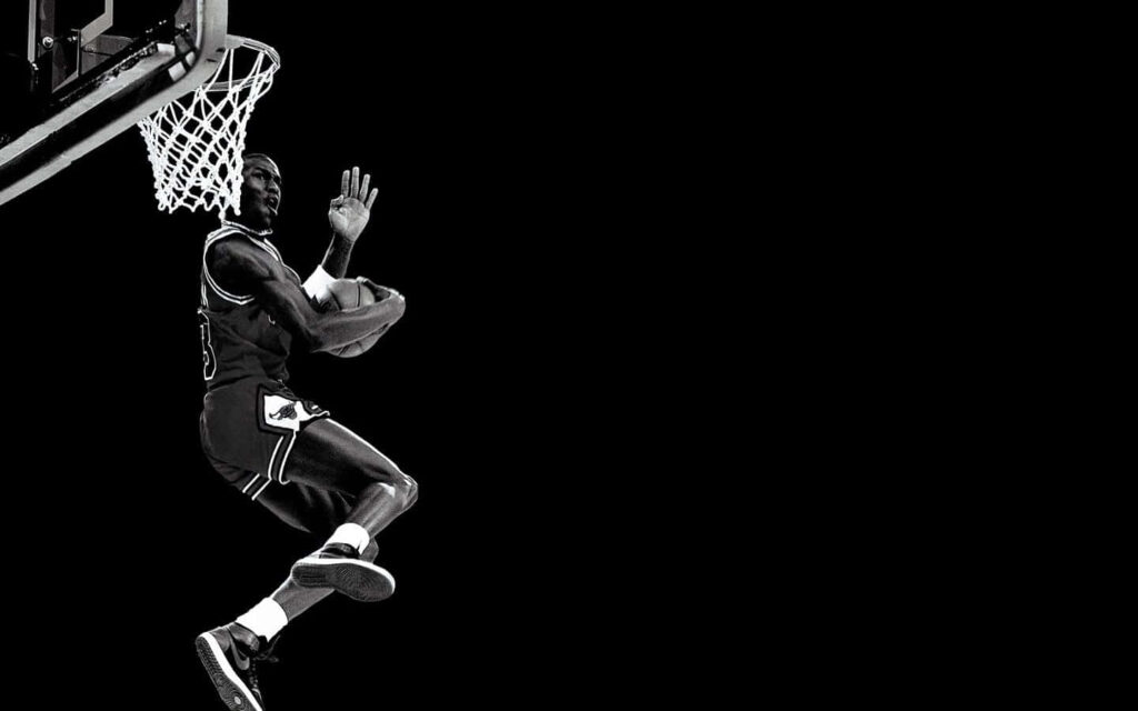 Airborne Elevation: The Iconic Jumpman Soars in the Shadows Wallpaper