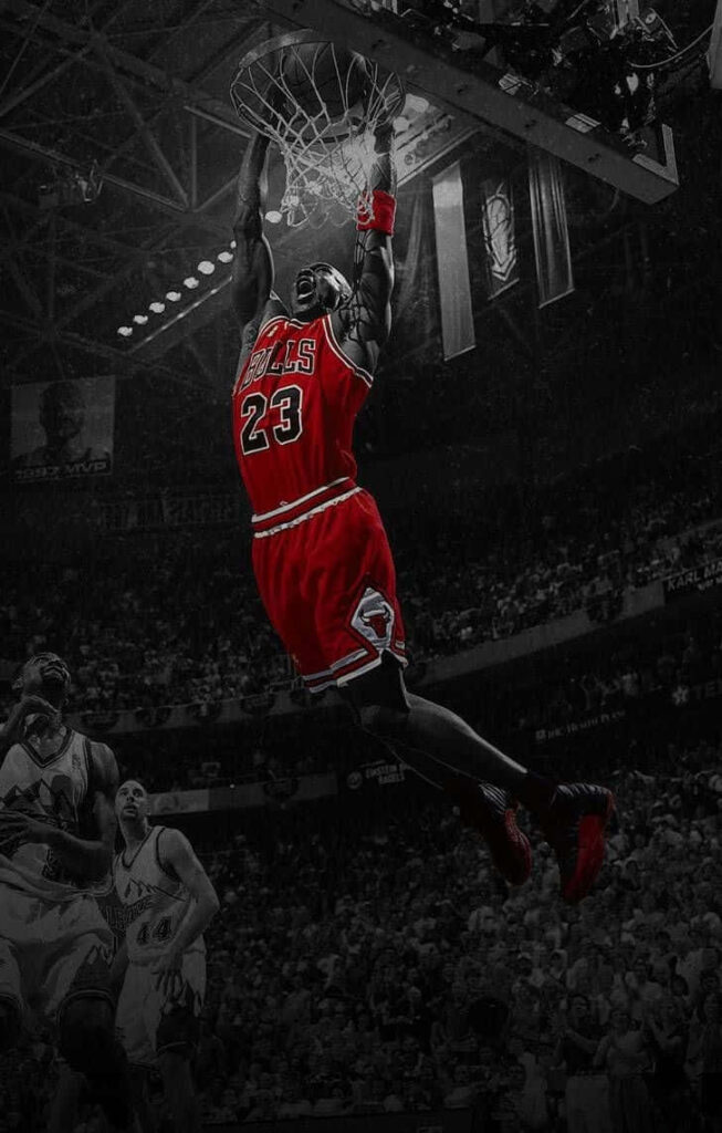 Airborne Dominance: Michael Jordan Soars above a Dimmed Crowd in a Slam Dunk Showstopper Wallpaper