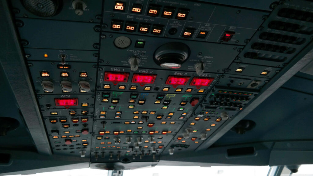 Aircraft cockpit overhead panel with illuminated switches and blue grey controls wallpaper background