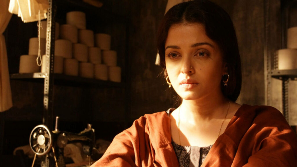 Aishwarya Rai in Sarbjit movie thoughtful pose by sewing machine with soft sunlight background Wallpaper