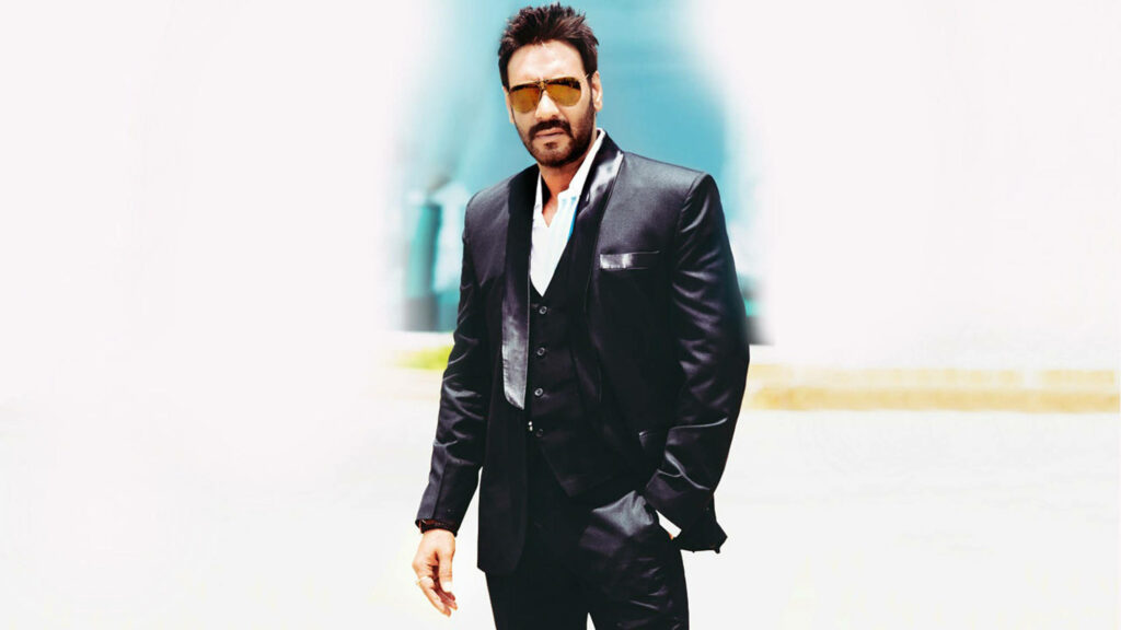 Ajay Devgn in black suit striking confident pose modern clean background wallpaper