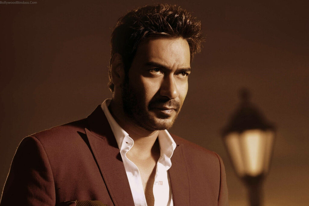 Ajay Devgn in stylish brown tuxedo and white shirt warm lit background wallpaper image