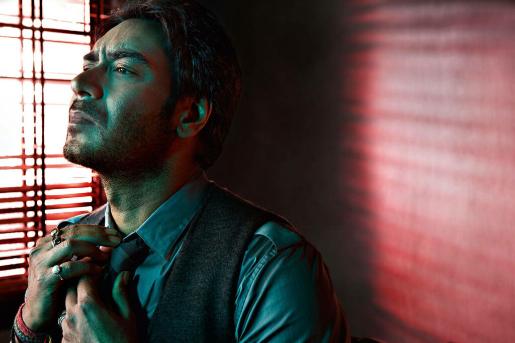 Ajay Devgn stylishly adjusts tie in dramatic window lighting during GQ photoshoot with wallpaper background