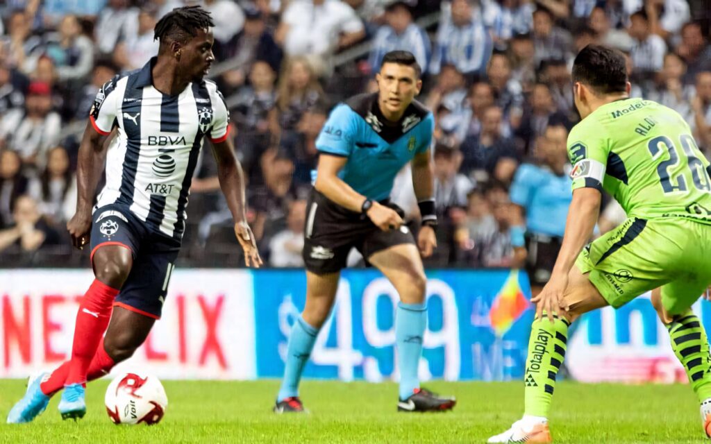 Aké Arnaud Loba controlling soccer ball with focus and agility during intense match crowd background Wallpaper