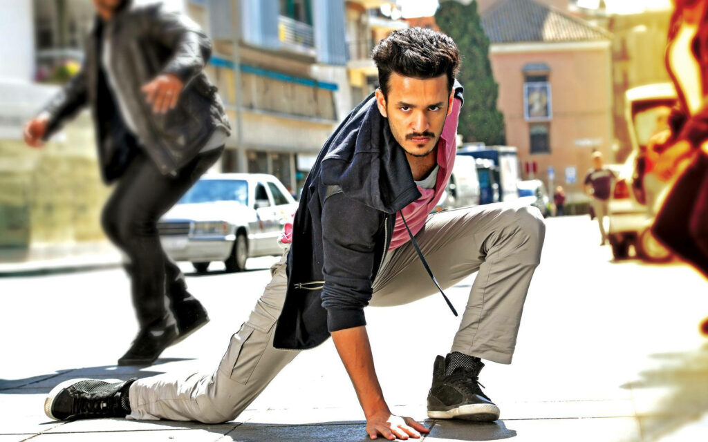 Akhil Akkineni intense action pose on city street vibrant wallpaper showcasing agility and strength
