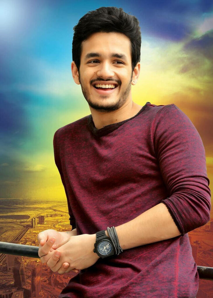 Akhil Akkineni leaning on railway railing with vibrant cityscape and colorful sky background Wallpaper
