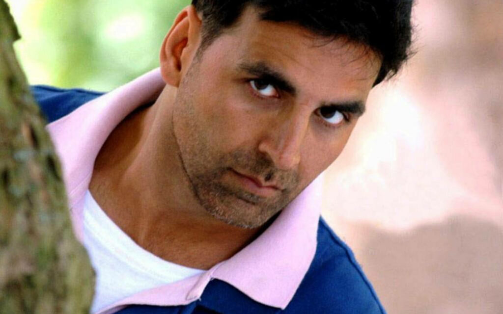 Akshay Kumar peeking behind tree with serious expression soft natural light wallpaper background