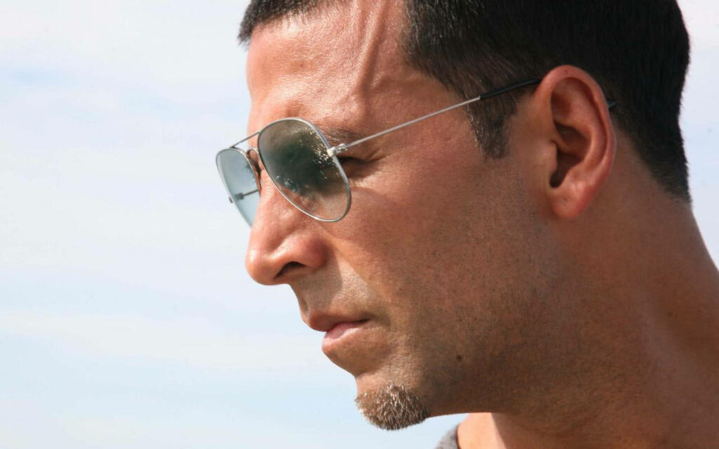 Akshay Kumar side profile with stylish sunglasses and calm sky background wallpaper