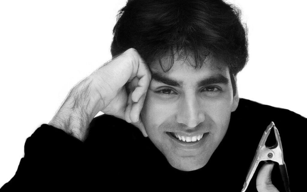 Grayscale wallpaper of Akshay Kumar smiling warmly with classic charm on white background