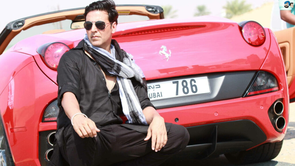 Akshay Kumar stylishly poses with a red Ferrari exuding confidence and charisma wallpaper background