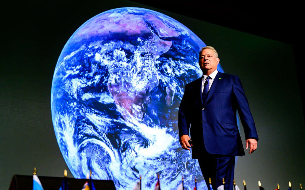 Al Gore speaking on stage with Earth background promoting climate change awareness and leadership Wallpaper