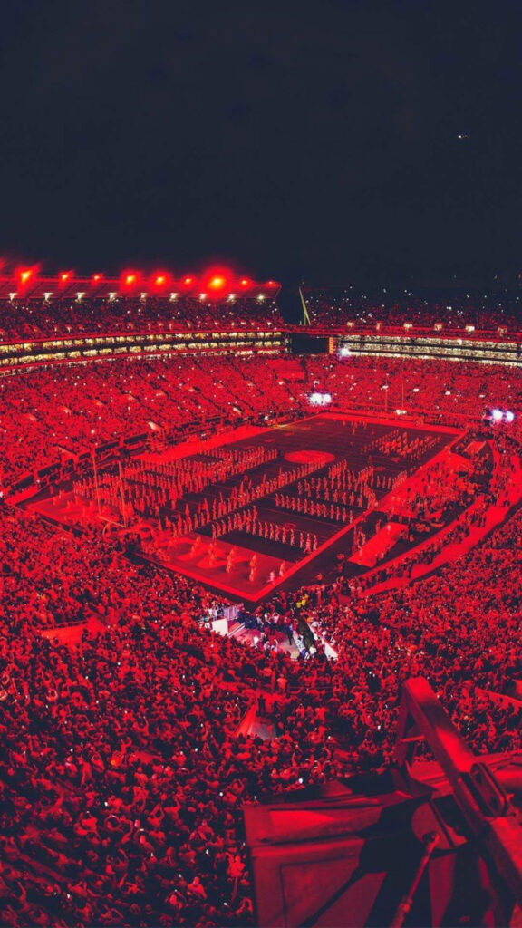 Night view of Alabama Crimson Tide football field filled with fans under red stadium lights Wallpaper