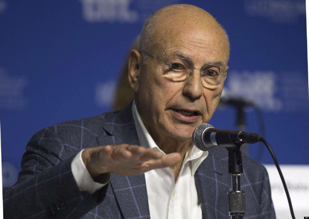 Alan Arkin speaking at press event serious expression microphone wallpaper background