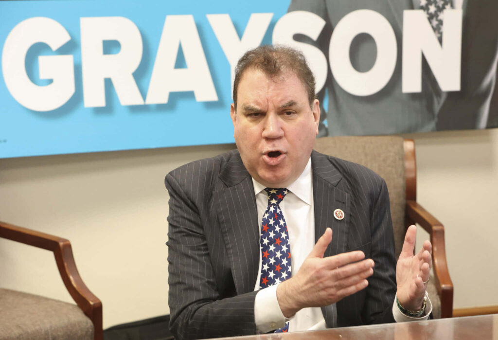 Alan Grayson American politician speaking passionately during live interview with name sign background Wallpaper