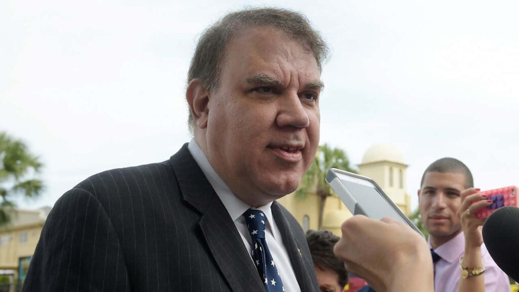 Alan Grayson American politician speaking to press outdoors with palm trees and buildings background Wallpaper