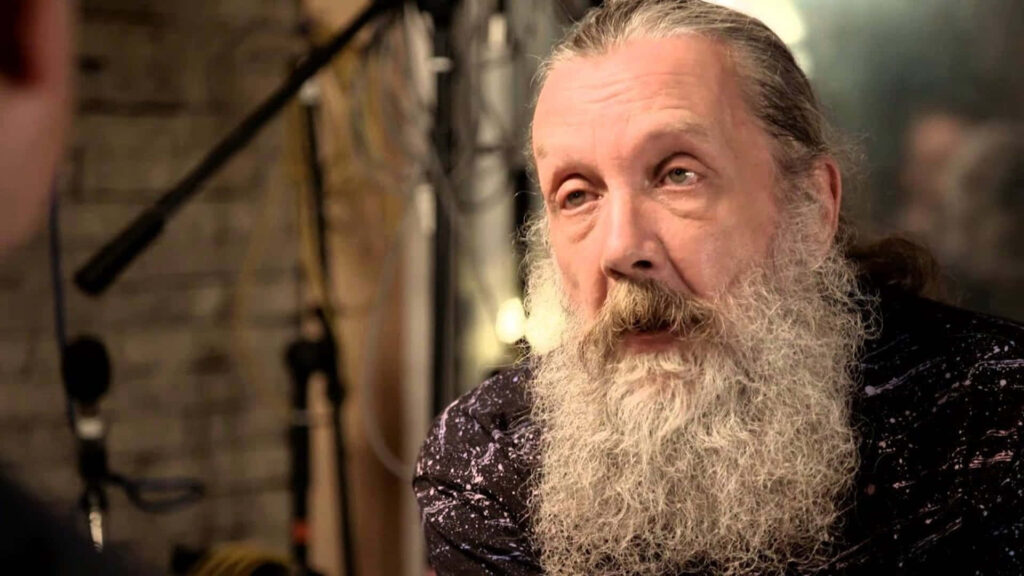 Alan Moore renowned writer candid at event showing wisdom creativity soft blurred background Wallpaper