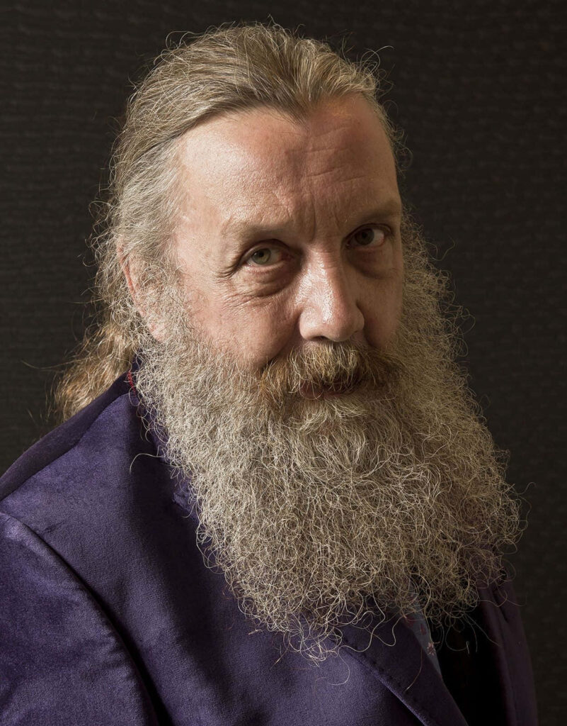 Alan Moore portrait wallpaper with long hair and beard on dark textured background for fans