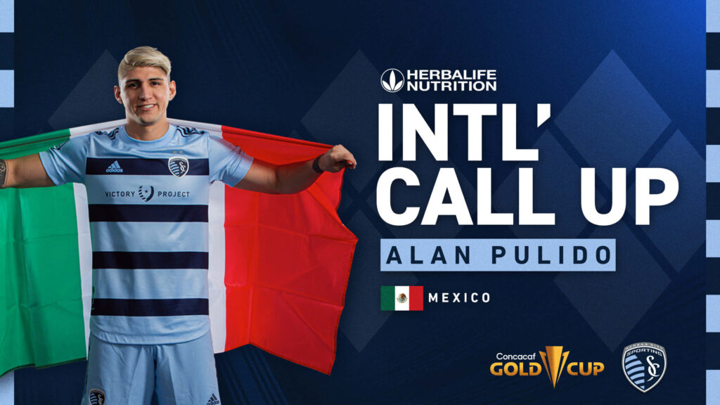 Alan Pulido celebrating Mexico international call-up holding flag in club jersey blue backdrop Wallpaper