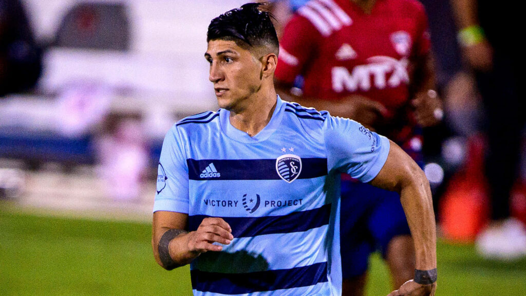 Alan Pulido in Sporting Kansas City jersey confidently walking on soccer field ready for action Wallpaper