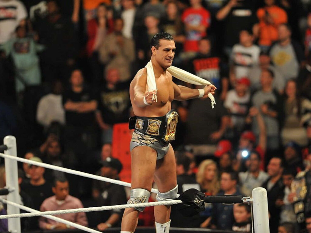 WWE superstar Alberto Del Rio on top rope holding championship belts in electrifying wrestling arena Wallpaper