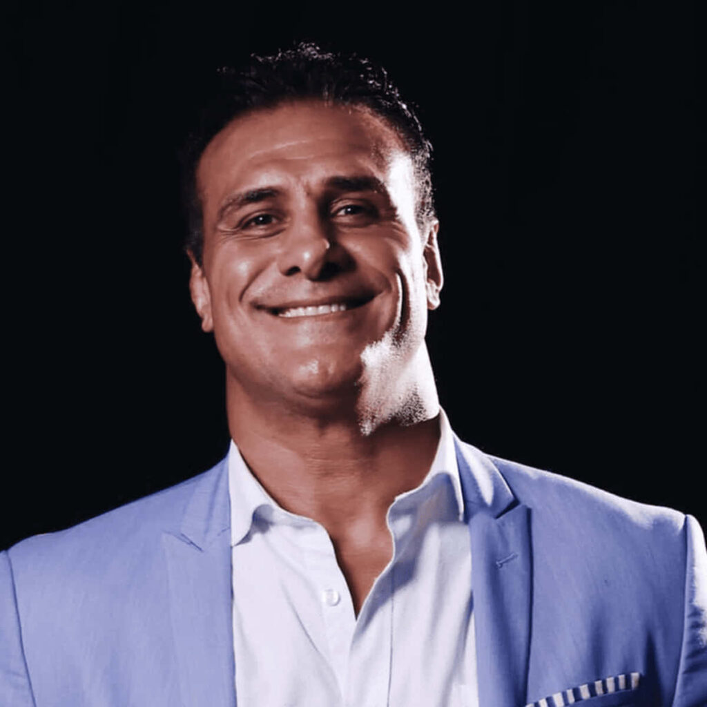 Close-up of Alberto Del Rio smiling confidently in light blue blazer dark background wallpaper
