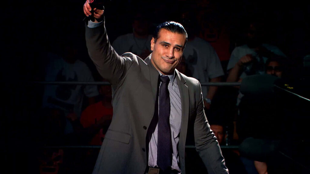 Alberto Del Rio in formal attire raising arm confidently in WWE ring with cheering crowd background Wallpaper