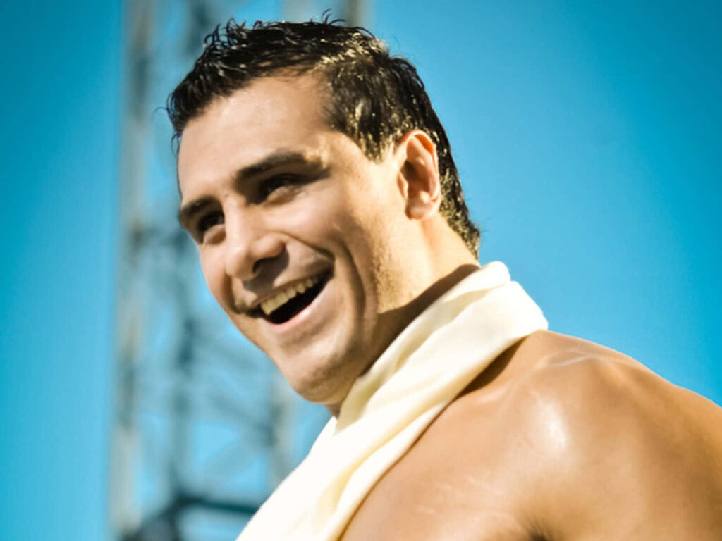 Alberto Del Rio smiling confidently against clear blue sky WWE star wallpaper background