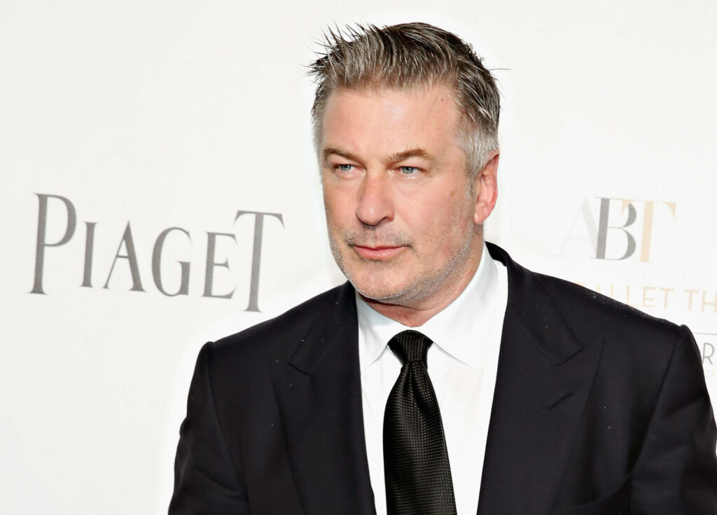 Alec Baldwin in classic black suit and tie at Piaget red carpet event posing against branded backdrop Wallpaper
