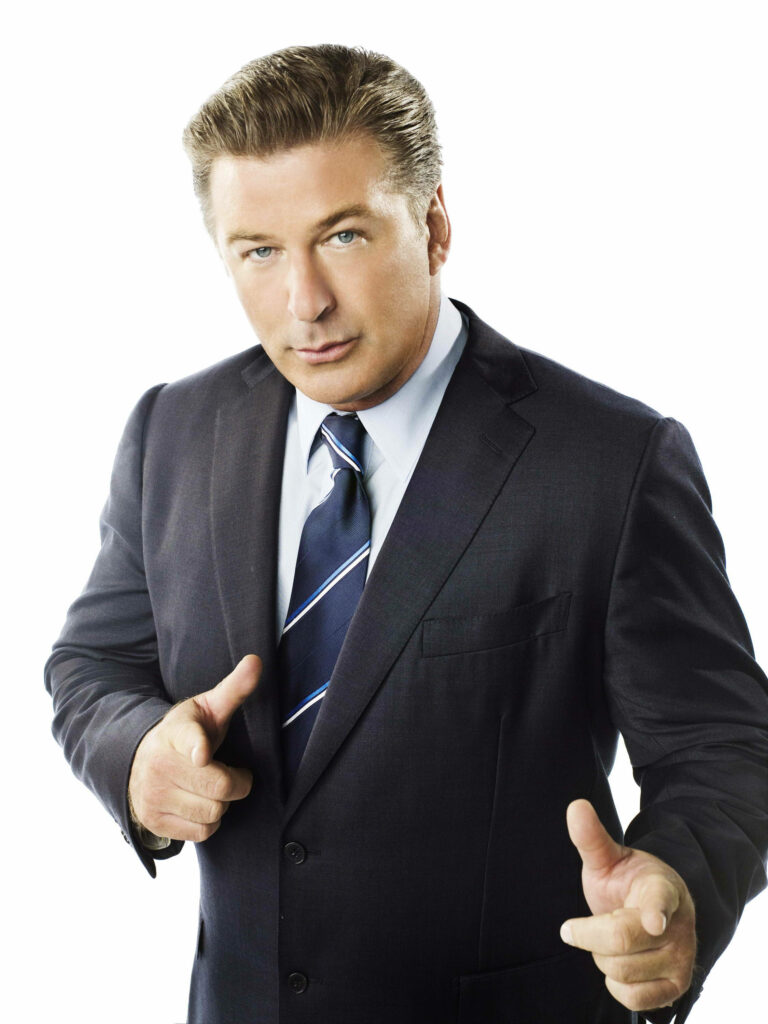 Alec Baldwin confident in sharp suit on white background striking charismatic wallpaper image