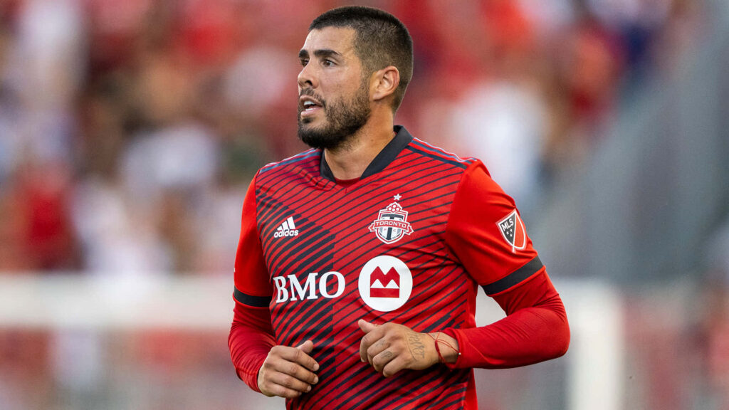 Alejandro Pozuelo in red Toronto FC jersey playing soccer in stadium during match action Wallpaper