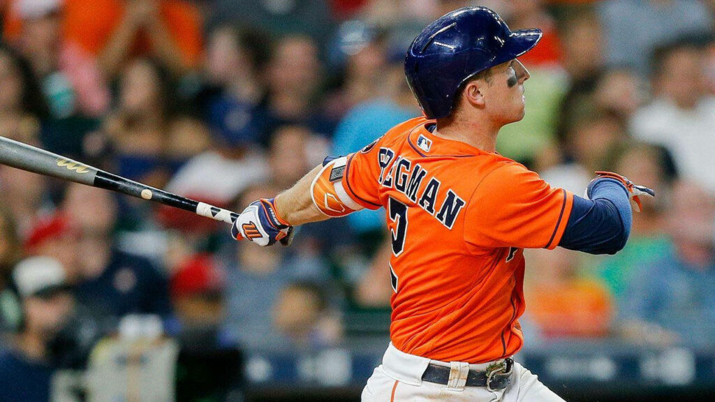 Alex Bregman swinging bat in orange Astros uniform showing focus and athleticism during game Wallpaper