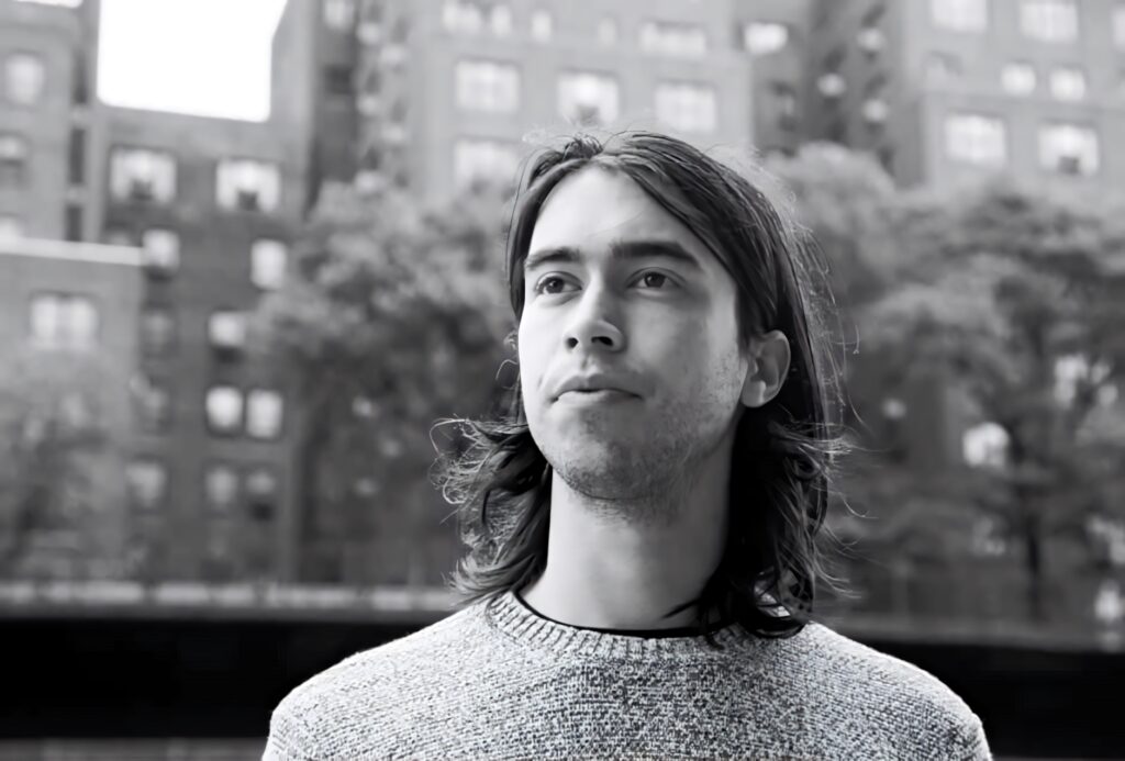 Alex G thoughtful outdoors cityscape background gazing into distance contemplative moment Wallpaper