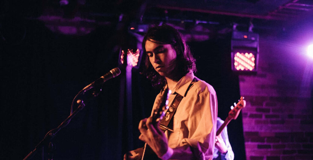 Alex G live on stage performing music under moody lighting creating intimate concert vibe wallpaper