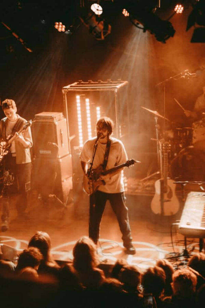 Alex G live concert guitar performance vibrant stage lighting enthusiastic fans wallpaper