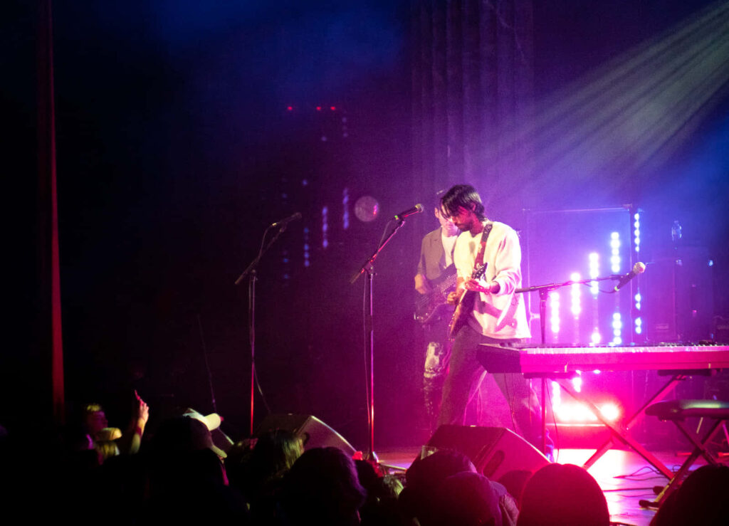 Alex G playing guitar live on stage vibrant concert lights energetic immersive atmosphere Wallpaper