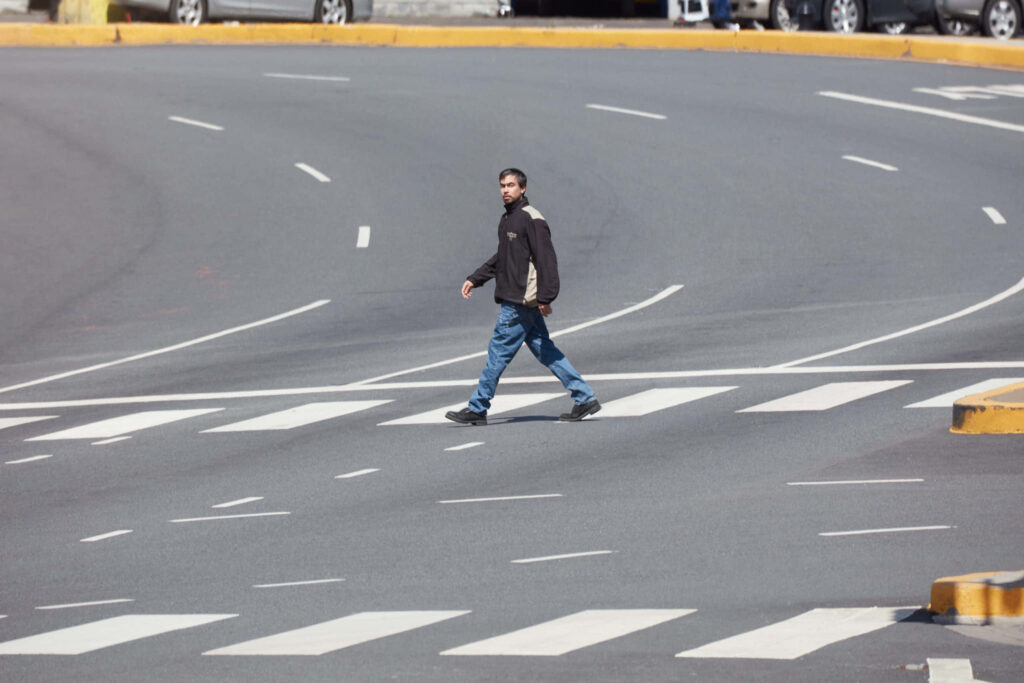 Alex G walking alone across empty urban intersection in city capturing quiet contemplative moment Wallpaper