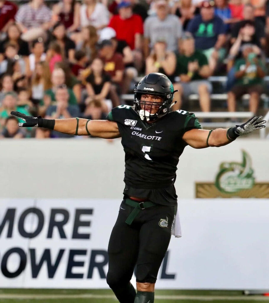 Alex Highsmith celebrating on Charlotte football field with arms outstretched in victory Wallpaper