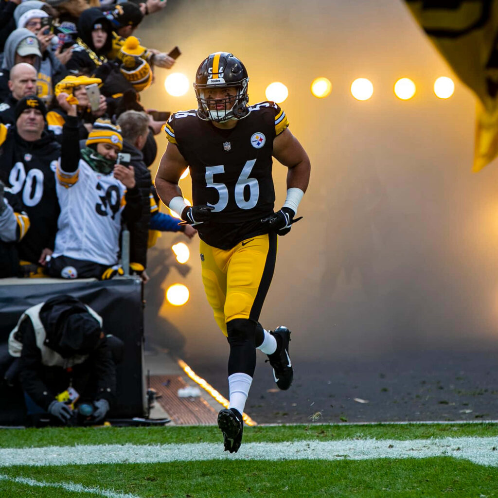 Alex Highsmith entering football field with cheering crowd and bright stadium lights background Wallpaper