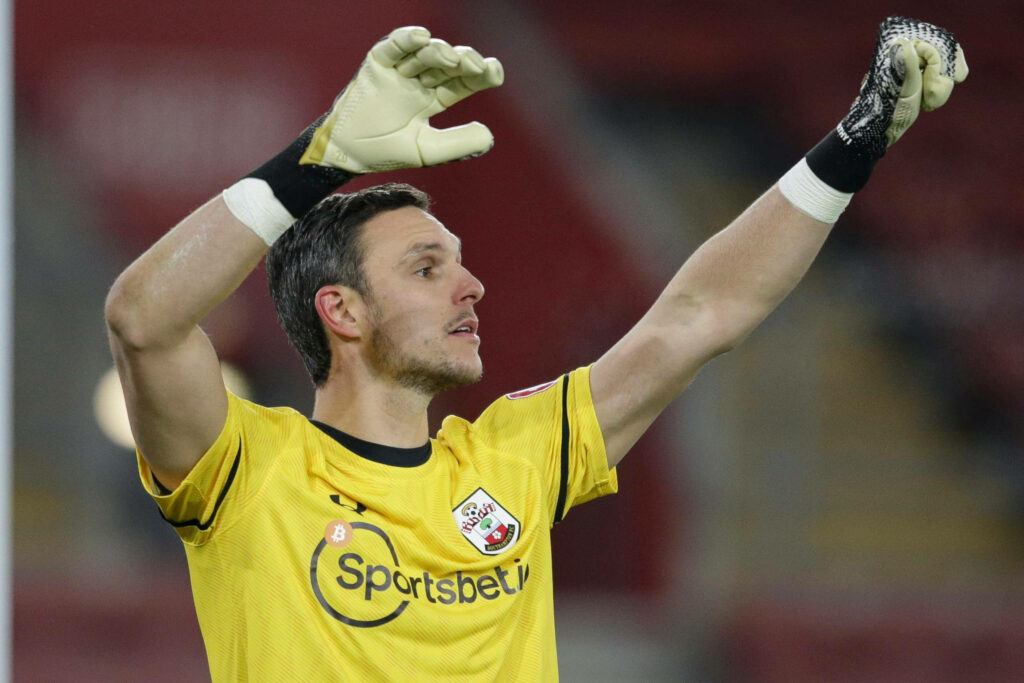 Alex McCarthy in yellow goalkeeper kit with arms raised ready for action on football pitch wallpaper