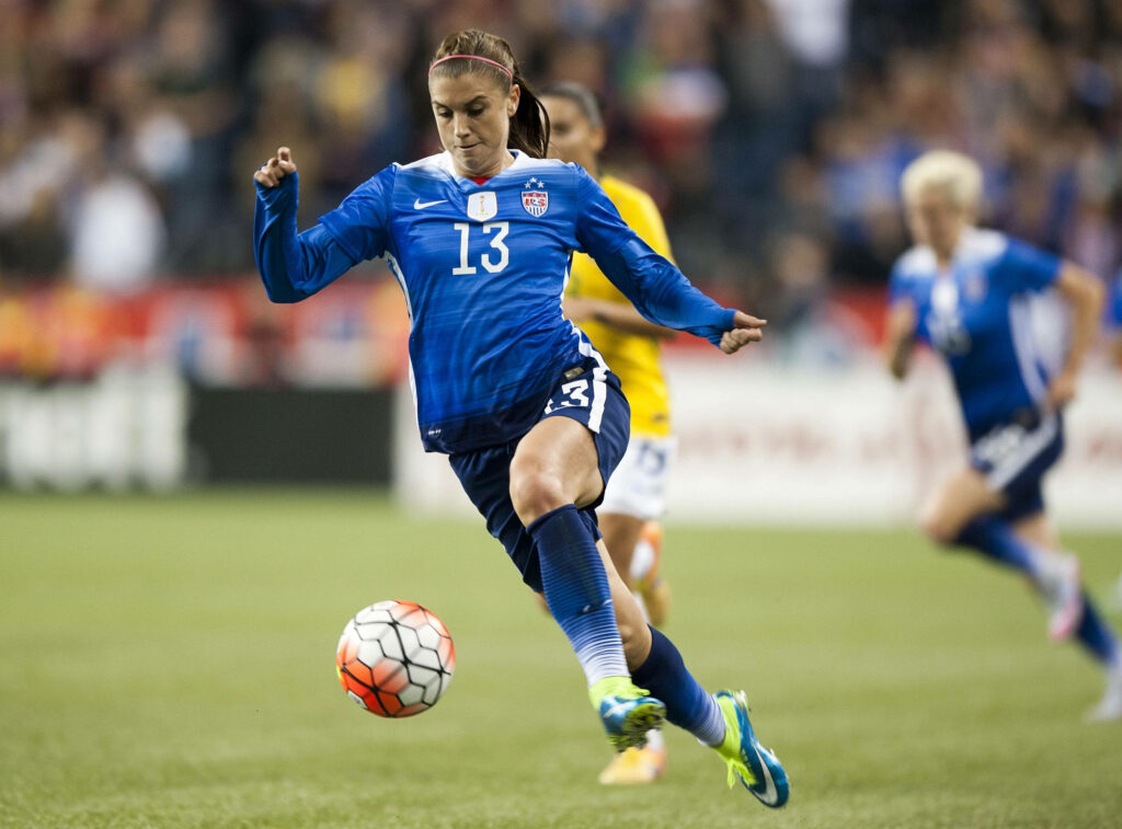Alex Morgan controlling soccer ball in vibrant blue USA jersey showing speed and focus wallpaper