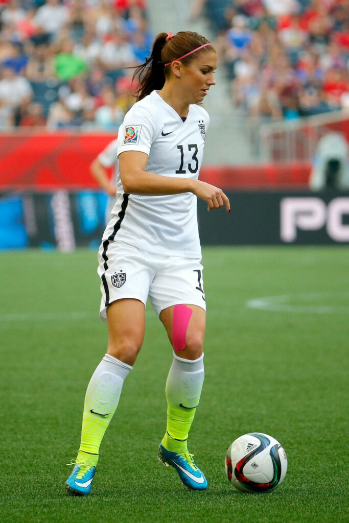 Alex Morgan focused on soccer field controlling ball in United States team uniform match wallpaper