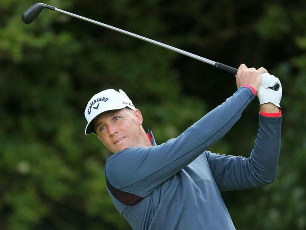 Alex Norén finishing golf swing focused poised on lush green golf course background wallpaper